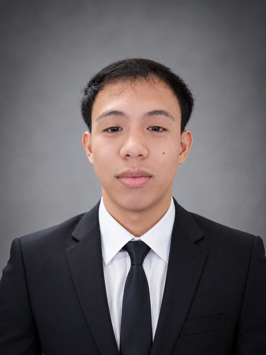 Junry Virtucio wearing a black suit against a gray studio background.